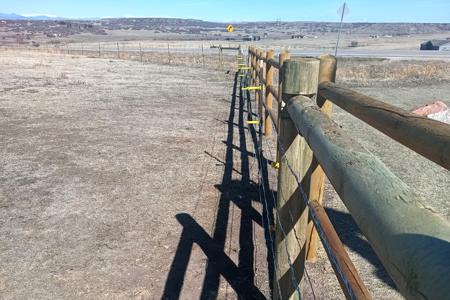 Fencing in Larkspur, Colorado. The hot wire is installed on the pasture fence to assure the cows don't rub against the new fence.