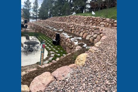 Retaining wall Monument Colorado. Installed a boulder retaining wall behind a home in Monument, Colorado to increase the back yard size and to keep the dirt and water from entering the back yard.